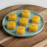 Seven pure beeswax tealight candles on a plate